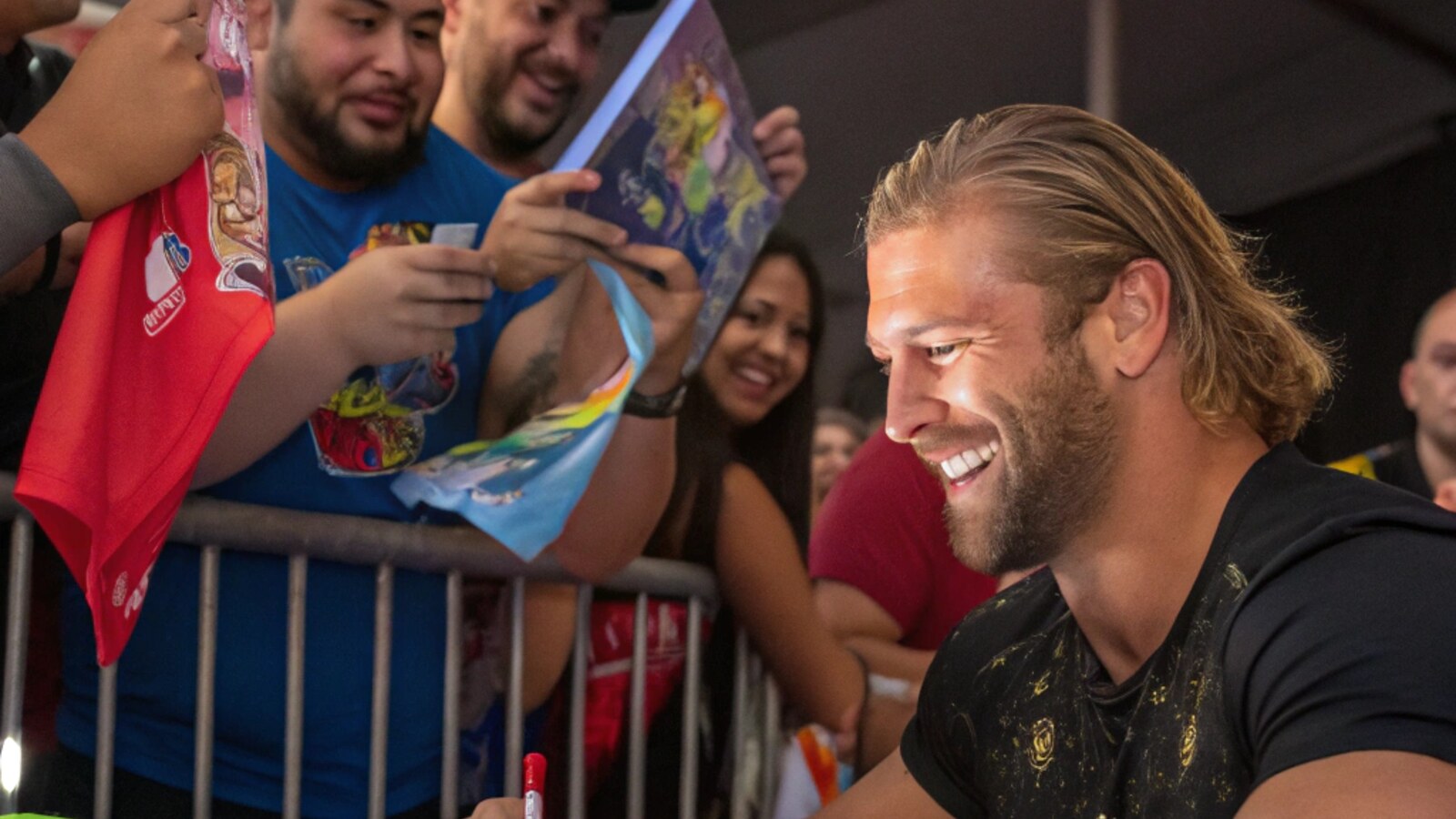 A wrestler signs autographs for fans at his table